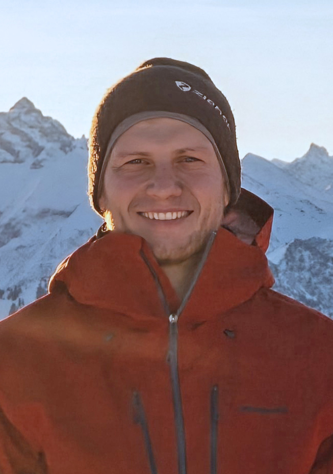 Porträtfoto von Manuel Fink vor verschneiter Bergkulisse.