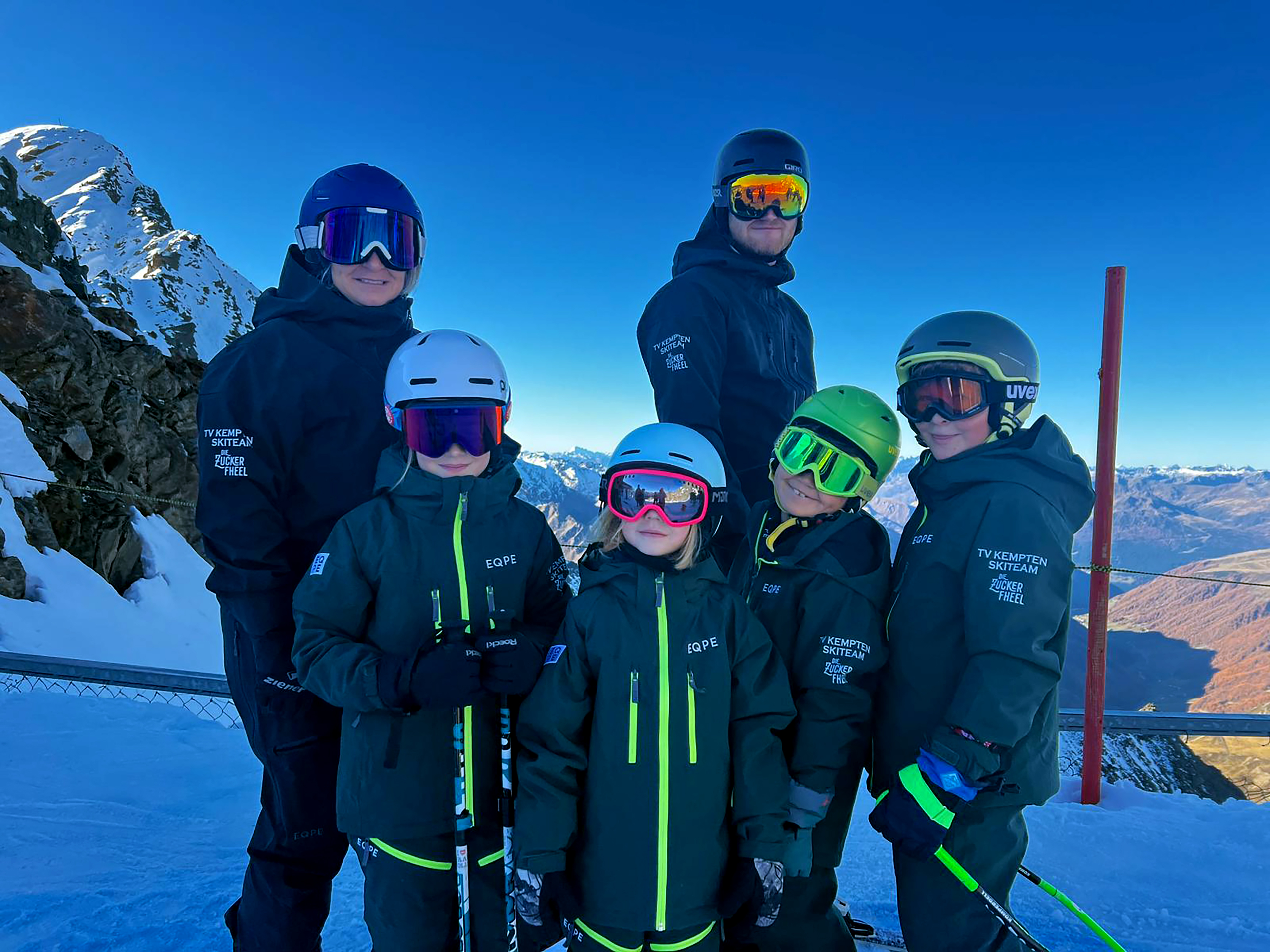 Skitrainer mit Kindern vor stahlblauem Himmel.