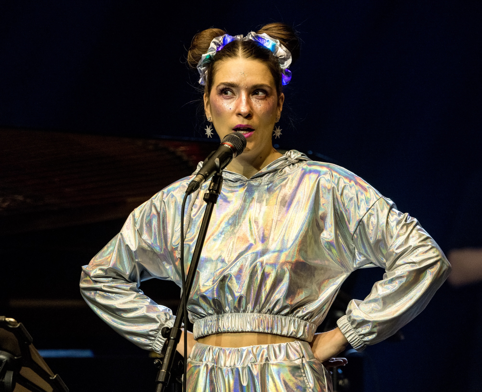 Leonie Leuchtenmüller im silberfarbenen Alien-Anzug am Mikrofon.