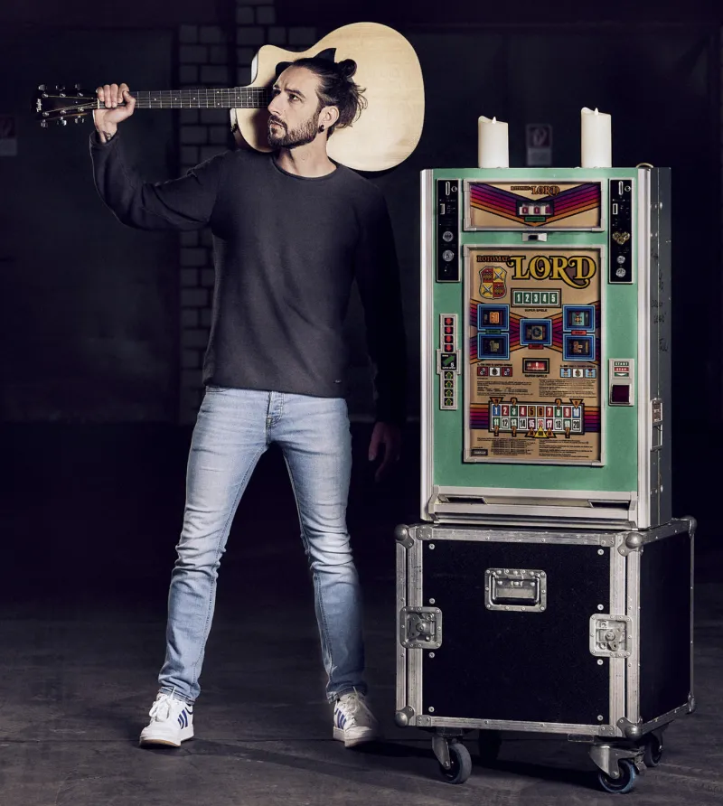 Aljosha Konter mit Equipment und Gitarre in cooler Pose.