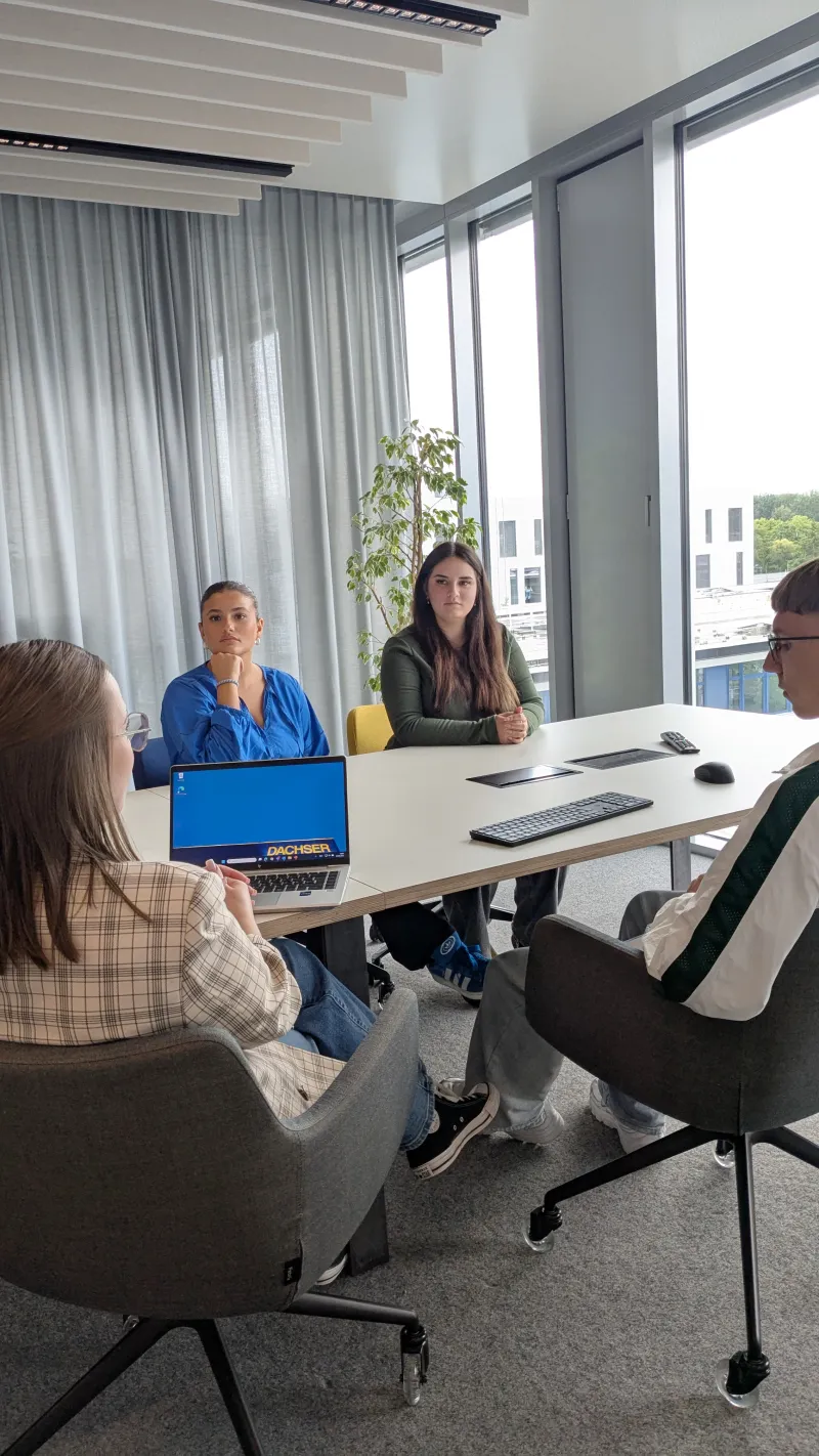 Vier Personen sitzen an einem Tisch zu einem Meeting.