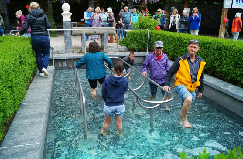 Menschen waten durch das Kemptener Kneipp-Becken.