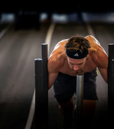 Sportler schiebt schweren Gegenstand.