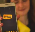 Ein Mädchen dass ein Handy in die Kamera hält auf dem "Closed" steht