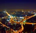 Bild einer Stadt und einer Autobahn bei Nacht, beleuchtet von tausenden Lichter