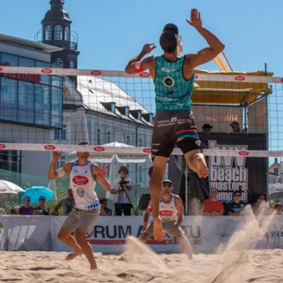 3 Männer spielen vor einem Publik am Forum Allgäu Beachvolleyball.