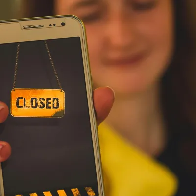 Ein Mädchen dass ein Handy in die Kamera hält auf dem "Closed" steht