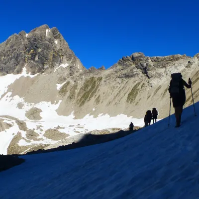 Wanderer auf einer Bergtour über einen teils verschneiten Gipfel.