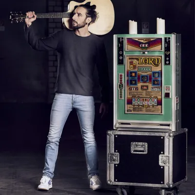 Aljosha Konter mit Equipment und Gitarre in cooler Pose.