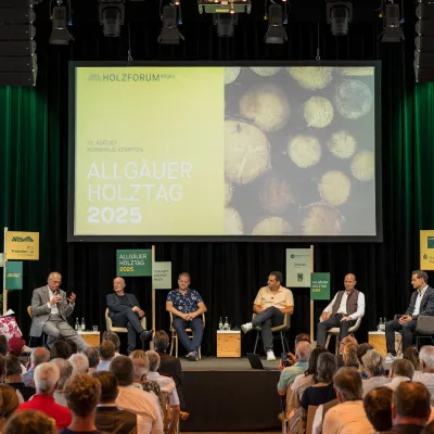 Foto von sitzenden Personen auf der Bühne des Allgäuer Holztages 2025.