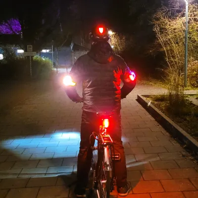 Radfahrer mit Rücklichtern am Rad, Helm und beiden Ellbogen.