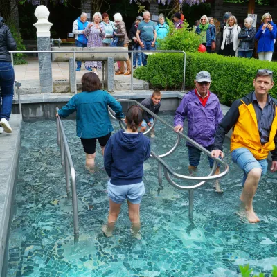 Menschen waten durch das Kemptener Kneipp-Becken.