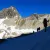 Wanderer auf einer Bergtour über einen teils verschneiten Gipfel.